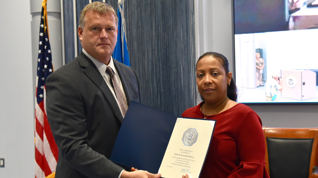 FLETC Acting Director William Fallon presents Stephanie Archbold-Massey with her 20 year service certificate