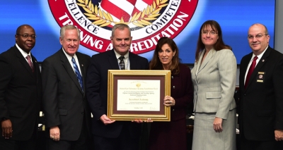 Defense Counterintelligence and Security Agency staff holding the FLETA accreditation certificate