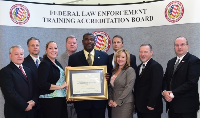 FLETC staff accept the certificate of accrediation.