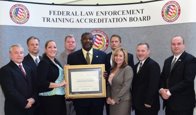 FLETC staff accept the certificate of accrediation. FLETC staff accept the certificate of accrediation.