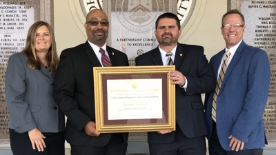 Representatives from the Naval Criminal Investigative Service hold the FLETA Accreditation Certificate Representatives from the Naval Criminal Investigative Service hold the FLETA Accreditation Certificate
